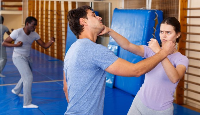 Adult people practicing effective techniques of self-defence in training room