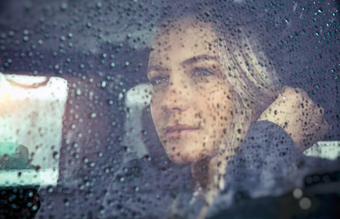 Porträt einer schönen, traurigen Frau, die bei Regenwetter im Auto sitzt, nachdenkliches Mädchen, das durch das Fensterglas mit Regentropfen schaut, Konzept der Herbstmelancholie