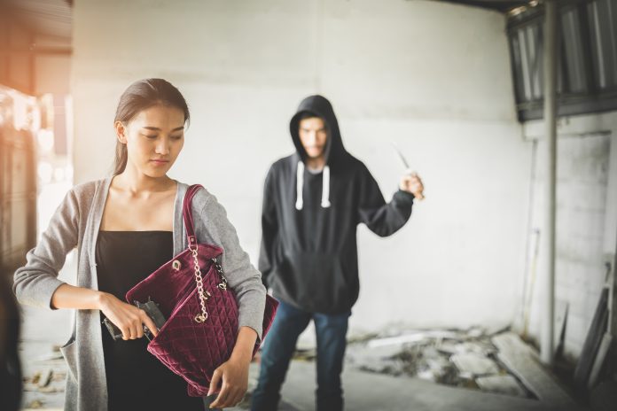 Woman pulls a gun from her swanky purse while the thief stood in the back. Conceal carry weapon for protection themselves concept. Selective focus.