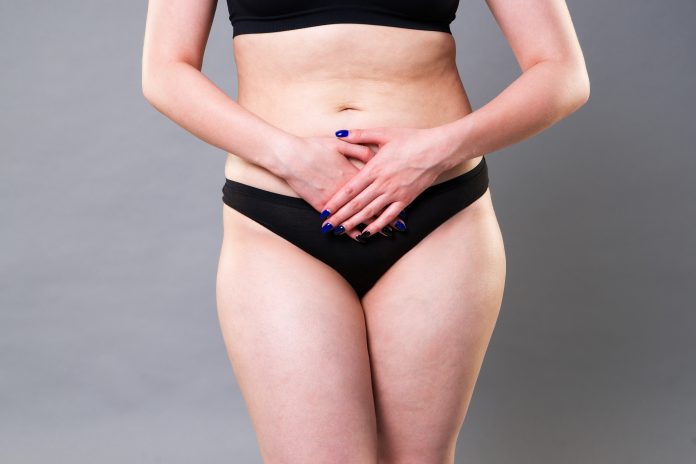 Mujer con dolor abdominal, dolor de estómago sobre fondo gris, foto de estudio