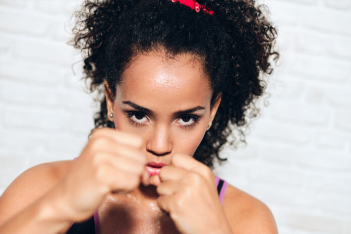 African american girl training in fitness club, gym, doing sport activity. Pretty young woman working out, fighting, boxing, exercising for self-defense