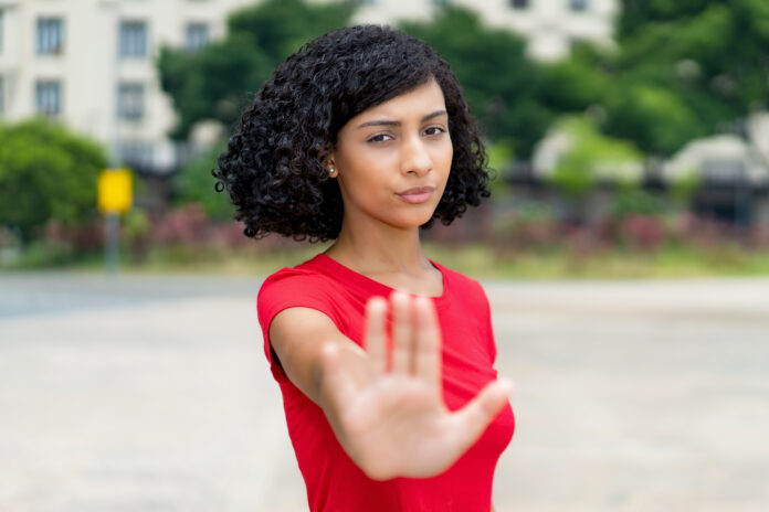 Mujer brasileña joven adulta con gesto de parada y distanciamiento social al aire libre en la ciudad