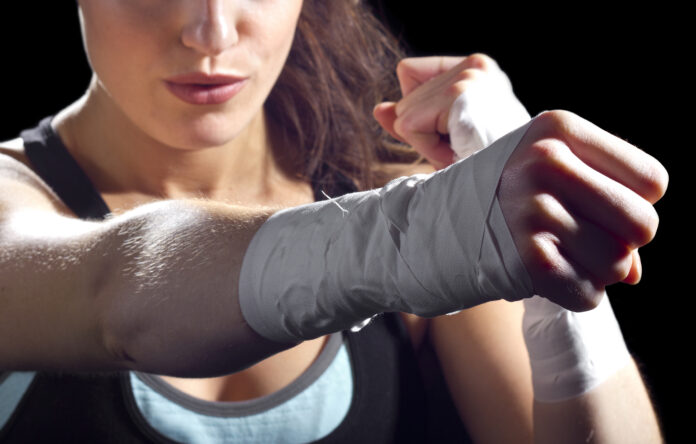 female MMA fighter punching.  black background