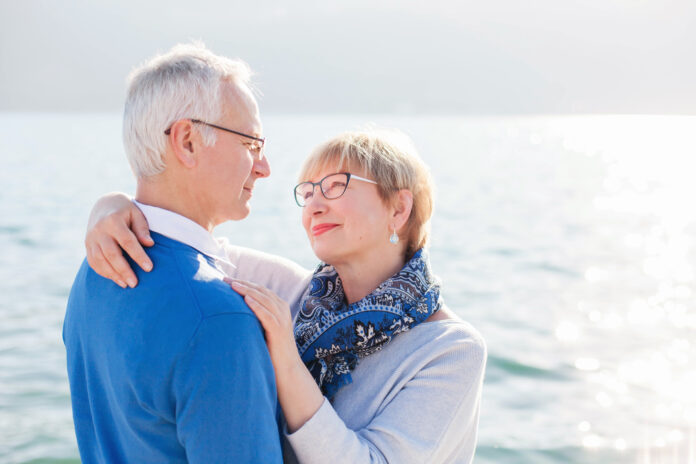 Feliz pareja de ancianos en la playa del mar al aire libre. El hombre y la mujer se abrazan, se abrazan, disfrutan de la jubilación y de la vida. Concepto de bienestar, felicidad, salud masculina y femenina, momentos de estilo de vida.