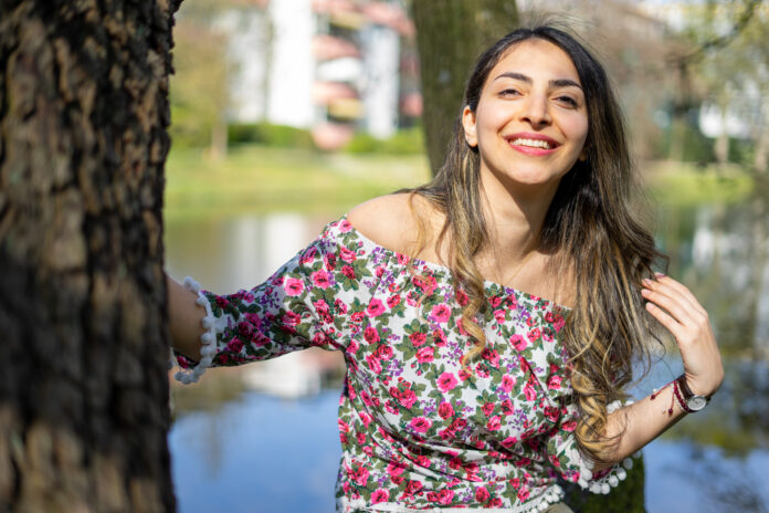 Middle east middle aged woman model posing in spring with a flowers blouse around a park in Bremen.