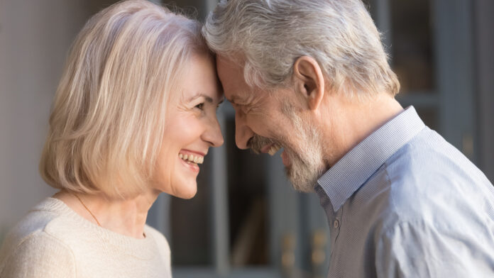 Portrait of happy elderly husband and wife touch foreheads look in eyes enjoy intimate romantic moment together, smiling mature couple having close tender time at home, lovers reunited at old age
