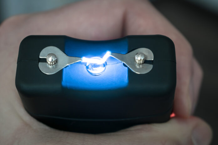 The use of a stun gun with a powerful electric discharge. Personal taser for protection against bandits is in the hands. . Turning on the device for self-defense. View from above