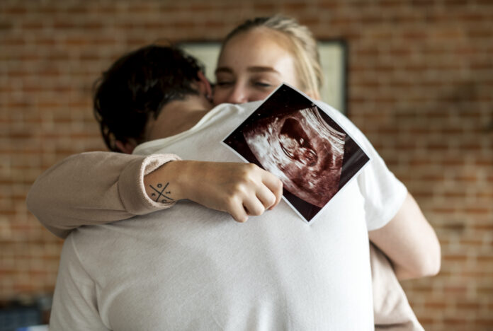 White couple with baby ultrasound photo