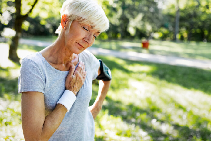 Frau mit Brustschmerzen durch Herzinfarkt beim Laufen