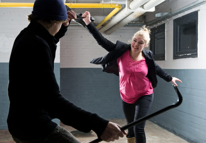 Young woman defending herself with her purse  against a criminal armed with a crowbar.