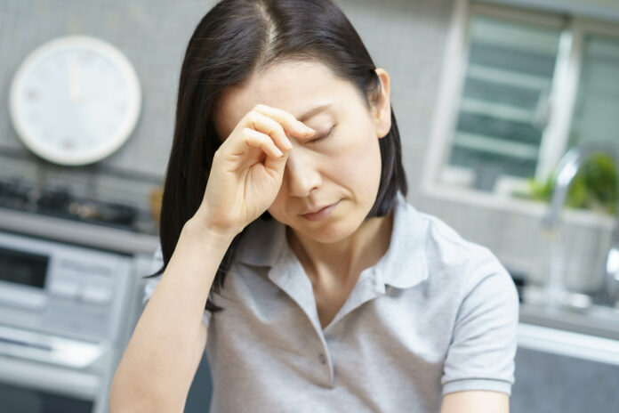 Asian middle-aged woman suffering from headache in the room