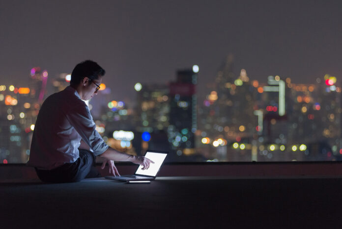 Business man working late with laptop computer on rooftop