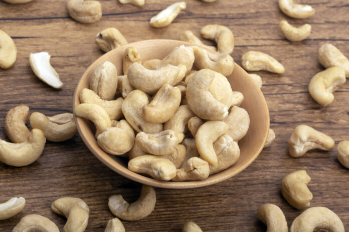 Cashew Nuts in a wooden bowl on brown background