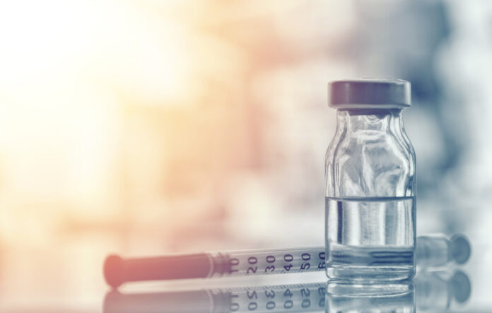 Nahaufnahme von Medizin Fläschchen oder Grippe, Masern-Impfstoff Flasche mit Spritze und Nadel für die Immunisierung auf Vintage medizinischen Hintergrund, Medizin und Drogen-Konzept