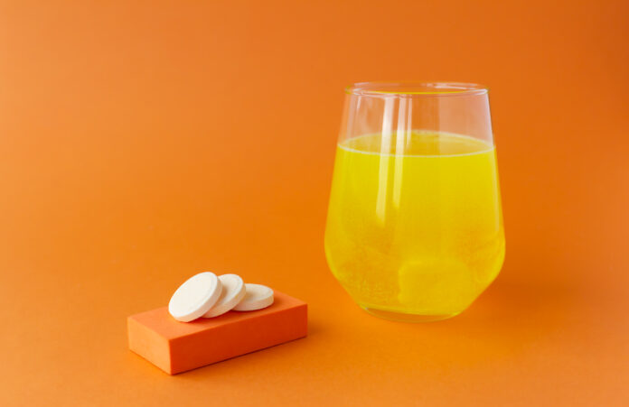 Effervescent vitamins, water-soluble tablets on orange backgrounds