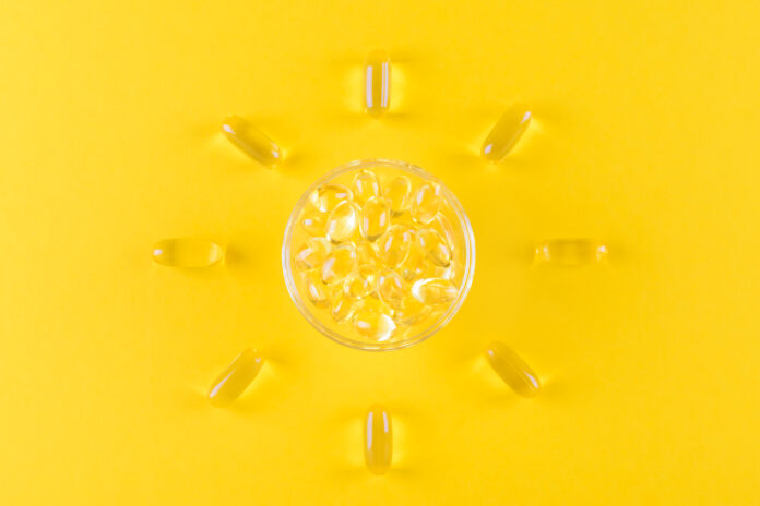 golden omega capsules like sun on yellow background, top view