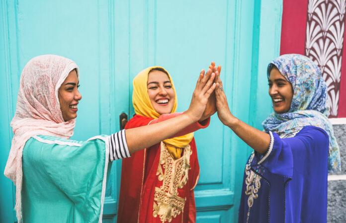 Happy Arabian women stacking hands together outdoor - Young Muslim women having fun and in the university - Concept of empowering, people, religion and team work