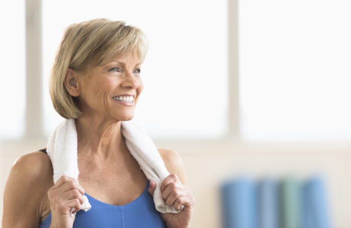 Happy mature woman with towel around neck looking away at home
