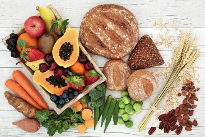 High fiber health food concept with fresh fruit, vegetables, wholegrain bread, nuts and cereals. Foods high in antioxidants, anthocyanins, omega 3 fatty acids and vitamins. Rustic background, top view.