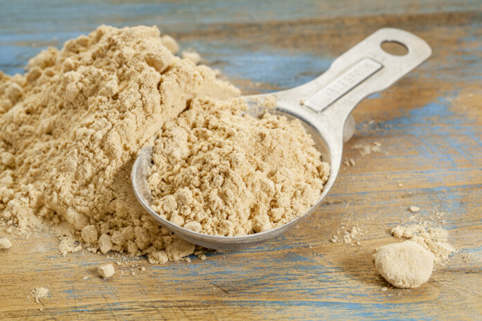 maca root powder - a measuring tablespoon and pile on wooden surface