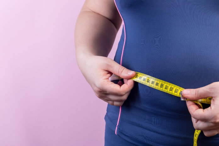 Overweight woman with measuring tape on a waistline, closeup
