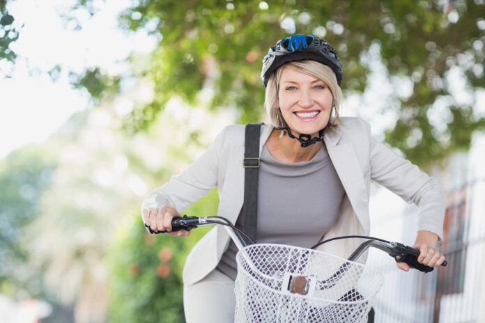 Portrait of cheerful businesswoman with bicycle in city