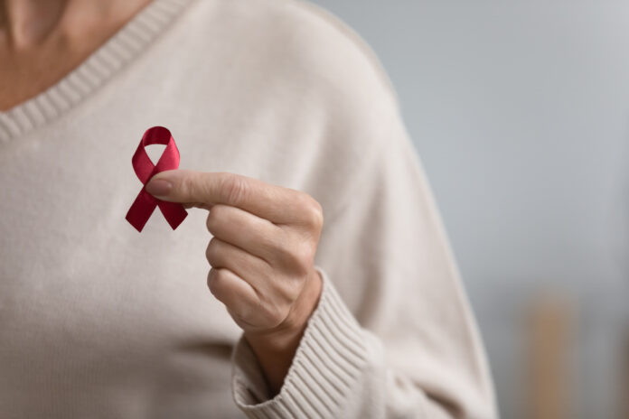 Nahaufnahme von Senior Frau halten rote Schleife Brustkrebs-Symbol Unterstützung Menschen Patienten mit Krankheit, mittleren Alters weiblichen Freiwilligen halten AIDS HIV Krankheit Bewusstsein, ältere Menschen Gesundheitswesen, Medizin-Konzept