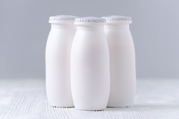 drei Getränkeflaschen Joghurt auf grauem Hintergrund