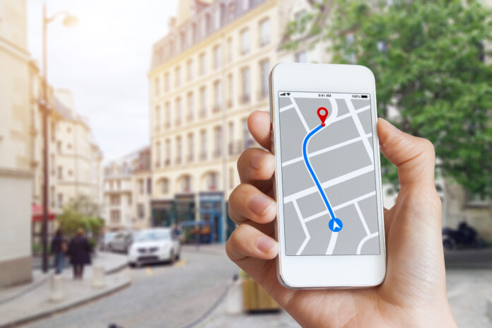 Tourist, der eine GPS-Kartennavigations-App auf dem Smartphone-Bildschirm verwendet, um die Richtung zur Zieladresse in den Straßen der Stadt zu finden, Reisen und Technologie