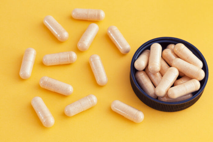 Vitamin B complex capsules on a yellow background. Close up.