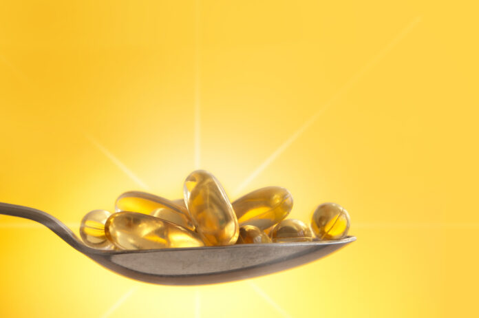 Vitamin D capsules on a spoon in sunlight