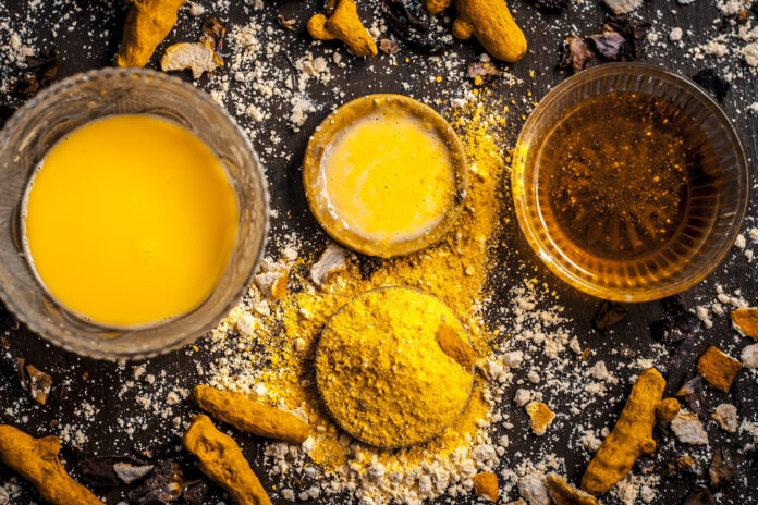 Close up of Ingredients of ayurvedic treatment or an ayurvedic face pack i.e Honey,chickpea flour and paste,turmeric powder and rose petals on a wooden surface.This face pack removes dead skin.
