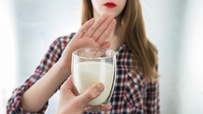 Lactose intolerance. Dairy Intolerant young girl refuses to drink milk - shallow depth of field. Selective focus on glass of milk
