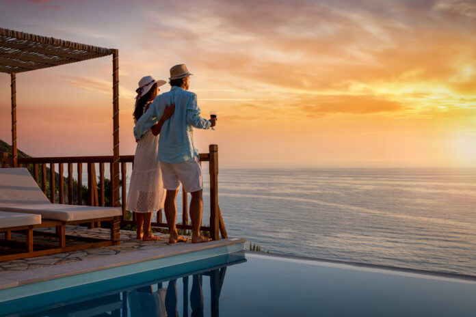 A romantic couple on summer vacation enjos the sunset over the mediterranean sea by the pool with a glass of Aperitif