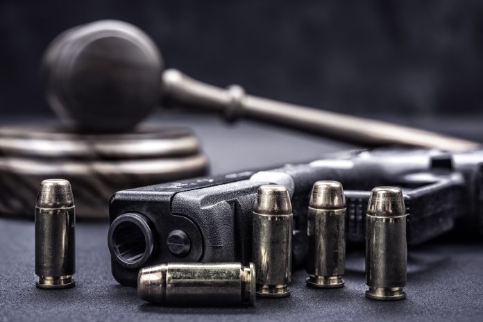 A handgun with bullets symbolizing gun rights while framed with a judge's gavel and block.