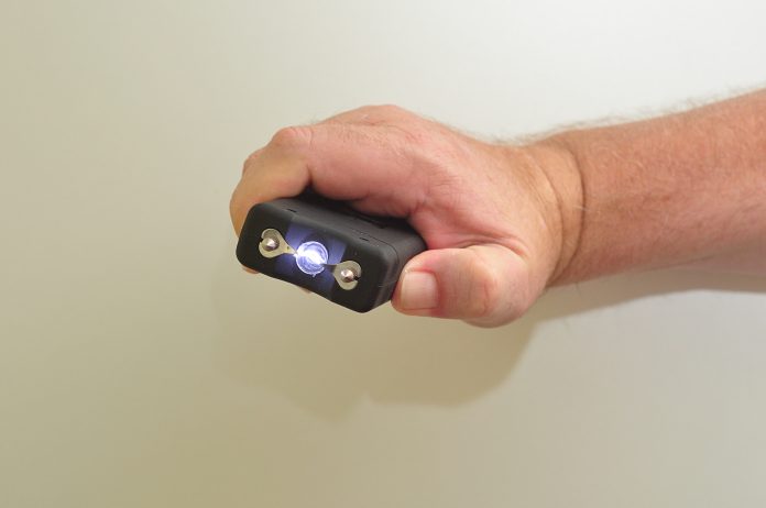 A taser held in a man's hand isolated on a white background