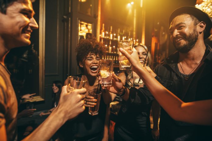 Ujęcie młodych mężczyzn i kobiet bawiących się na imprezie. Grupa przyjaciół pijących drinki w klubie nocnym.