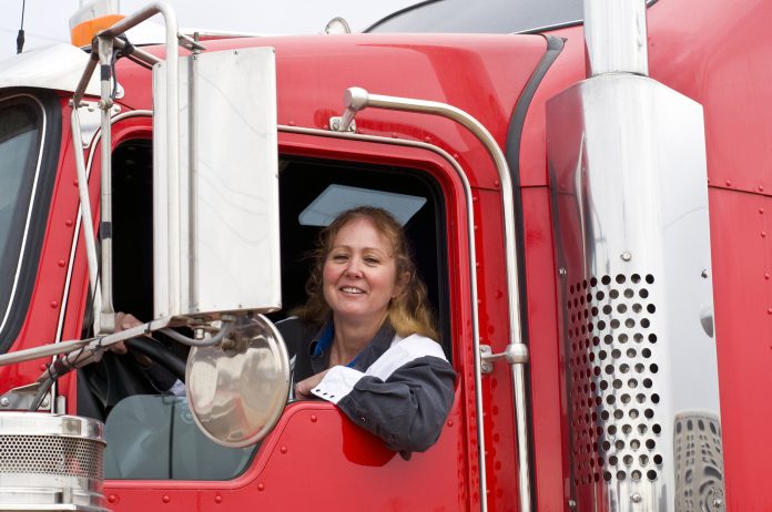 Woman truck driver leaning out the drivers side window of an eighteen wheeler