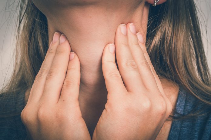 Vrouw met keelpijn houdt haar pijnlijke keel vast - concept van lichaamspijn