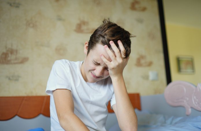 Child sitting on bed with headache. Negative emotions