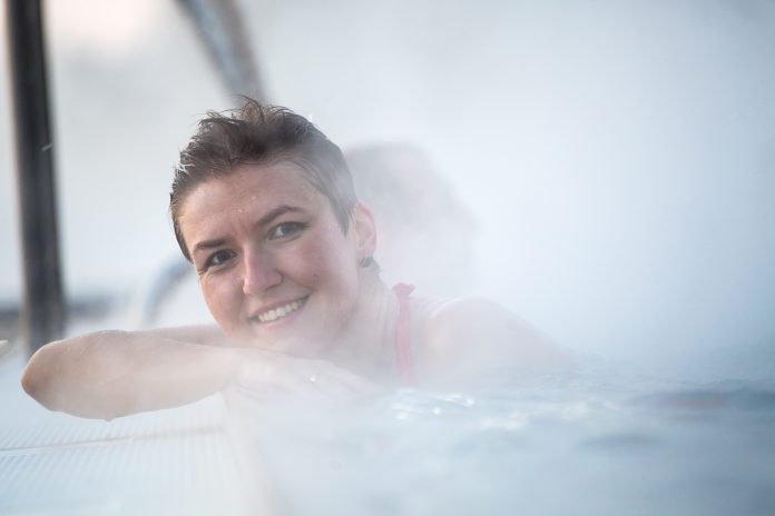 Happy young woman relaxing in thermal pool.