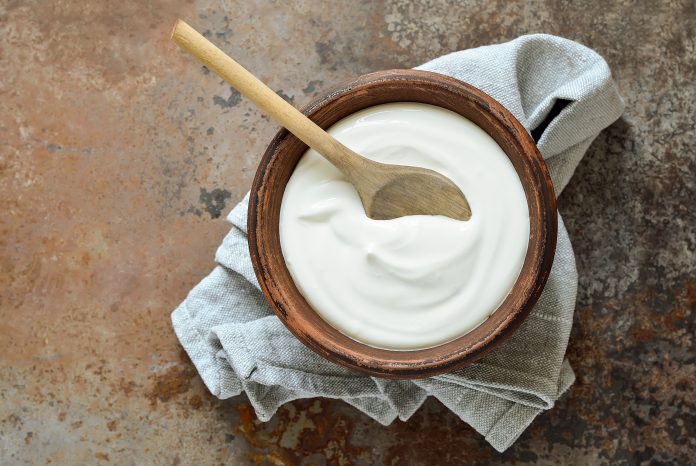 Homemade yogurt or sour cream on a rustic background, view from above