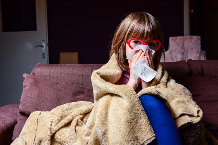 Portrait of sick little girl aged 7 siting in living room.