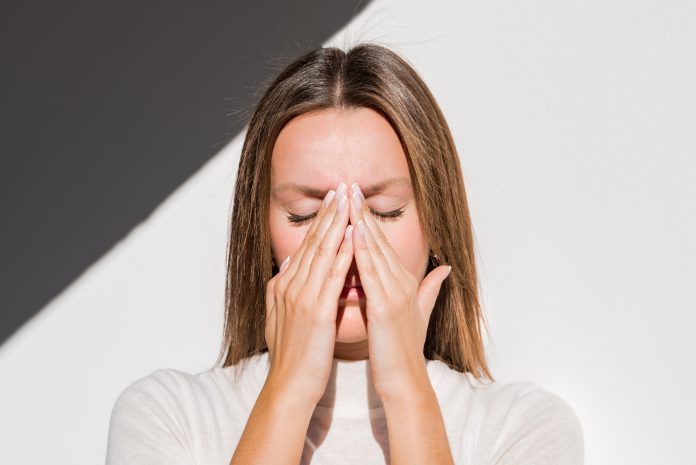 Woman feeling unwell, painful headache because of sinus ache, sinusitis, sinus pressure. Sad woman holding her nose and head because sinus pain. Black and white photo. High quality photo