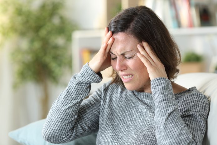 Frau mittleren Alters leidet zu Hause unter Kopfschmerzen