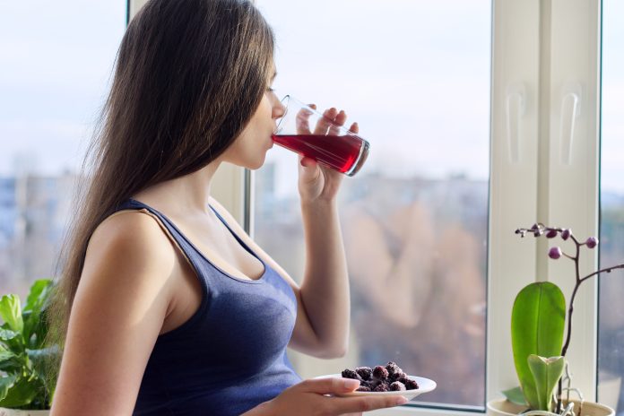 Young woman drinking natural fresh berry juice from a glass, closeup
