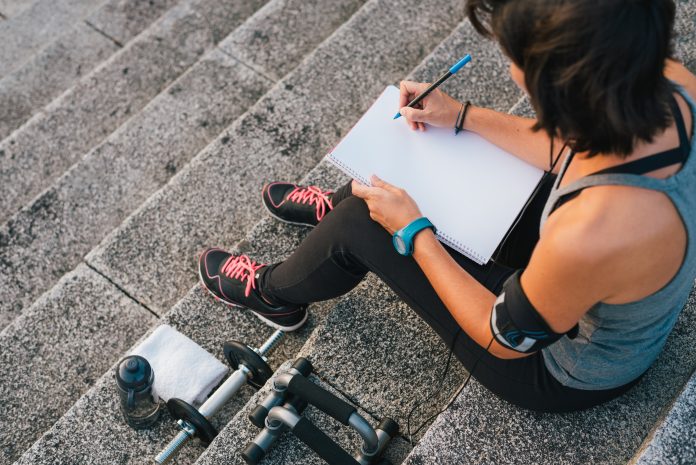 Urban female athlete focusing on her goals writting on notepad